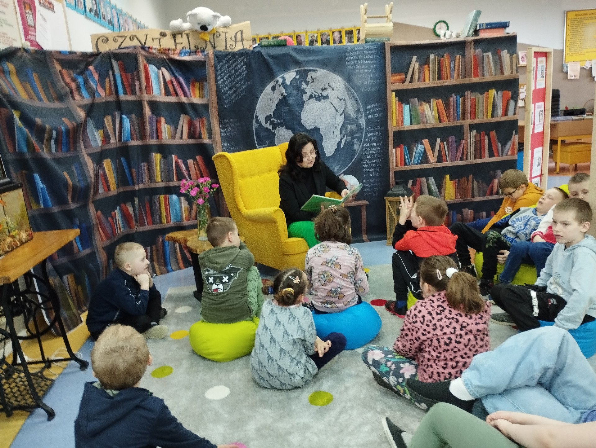 Pani Magdalena czyta książkę, dzieci siedzą na dywanie ii uważnie słuchają
