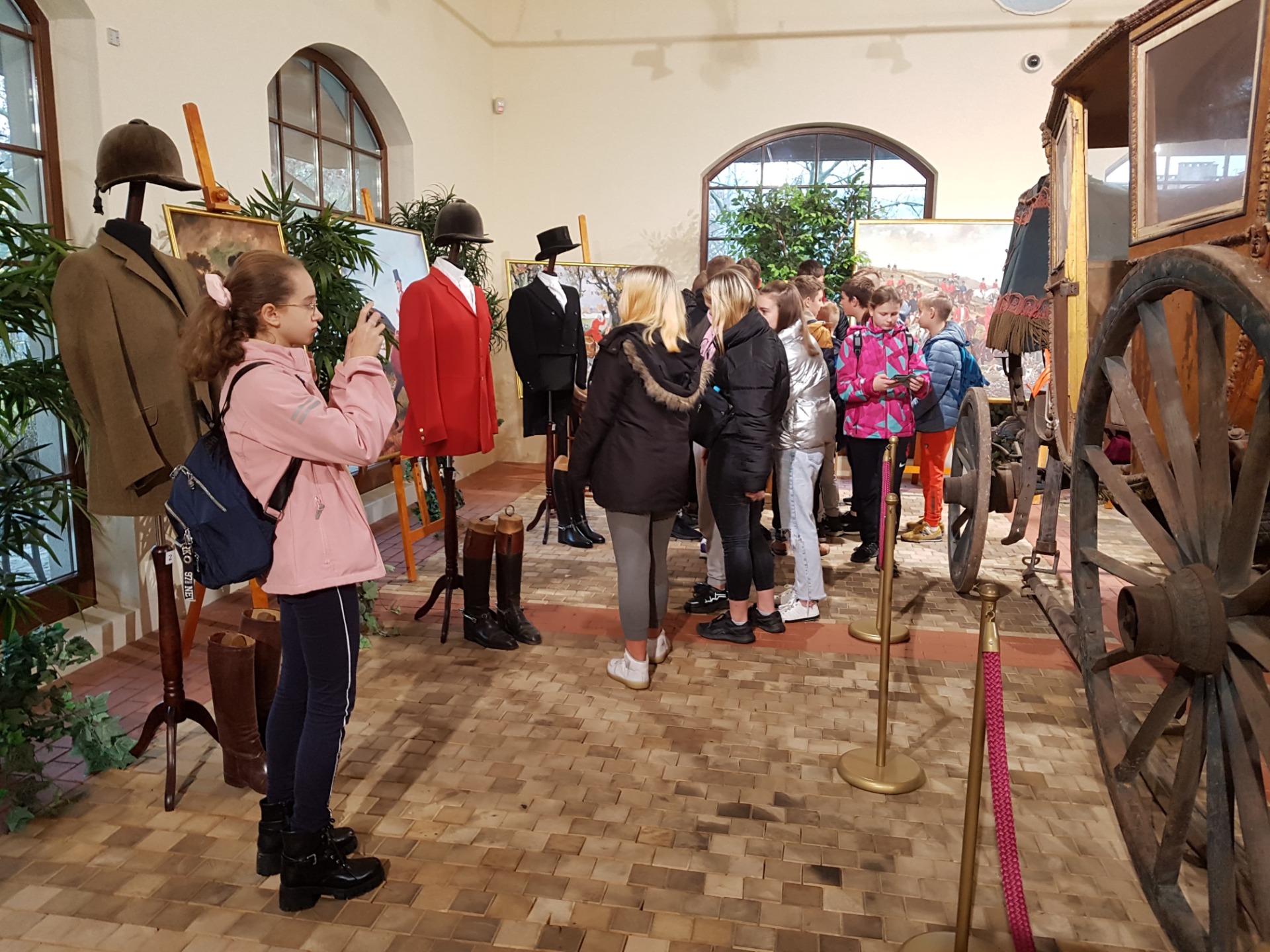 Grupa uczniów zwiedzających ekspozycje muzealne w Opinogórze.