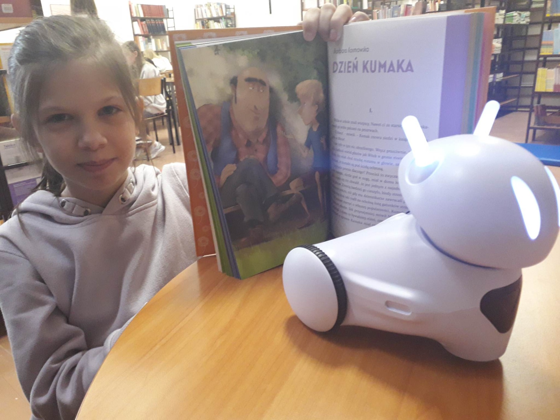 Ola Soska ucz. klasy IVa z książką oraz robotem Photon