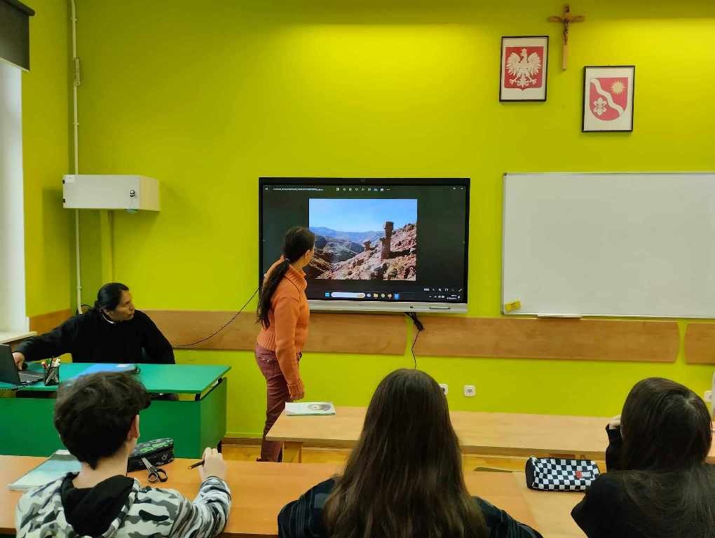 Na zdjęciu zaproszeni goście przedstawiający slajdy i opowiadający o życiu w Ameryce Południowej. Przed nimi siedzą uczniowie klasy ósmej.
