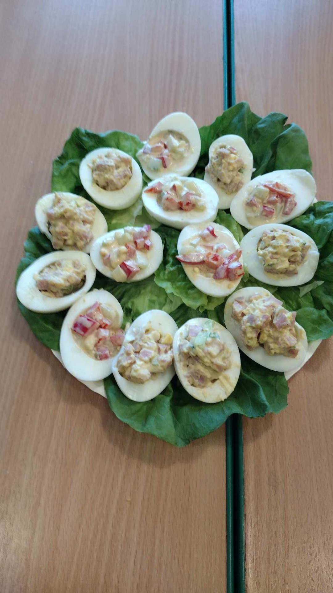 Jajka faszerowane ułożone na liściach sałaty na talerzu.