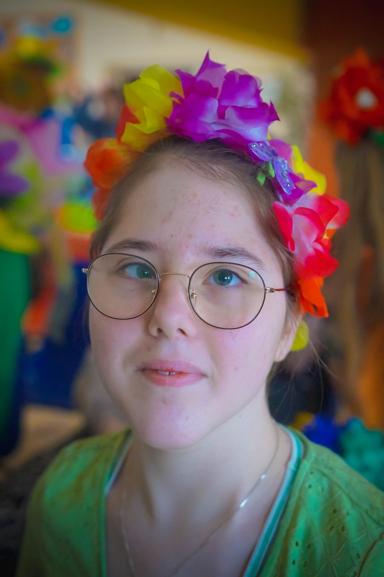 Uczennica w okularach, zdjęcie portret, na głowie ma kwiaty z bibuły