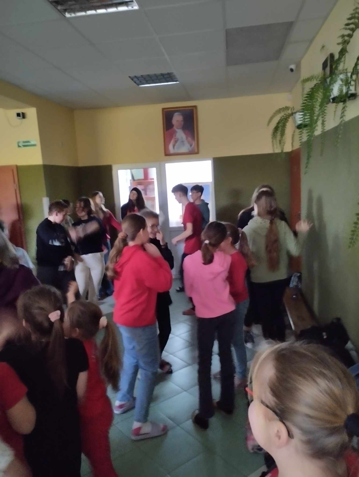 Uczniowie tańczą na szkolnym korytarzu.