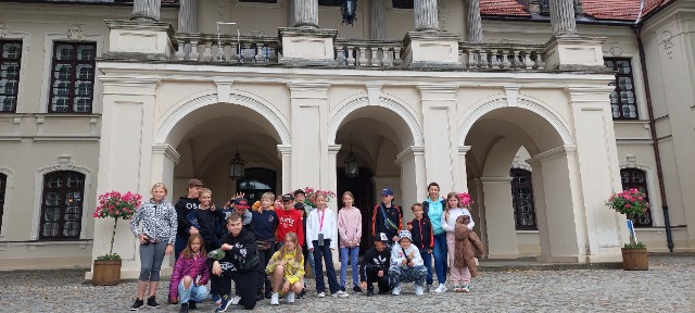 Grupa uczniów stoi przed wejściem do Pałacu Zamojskich w Kozłówce
