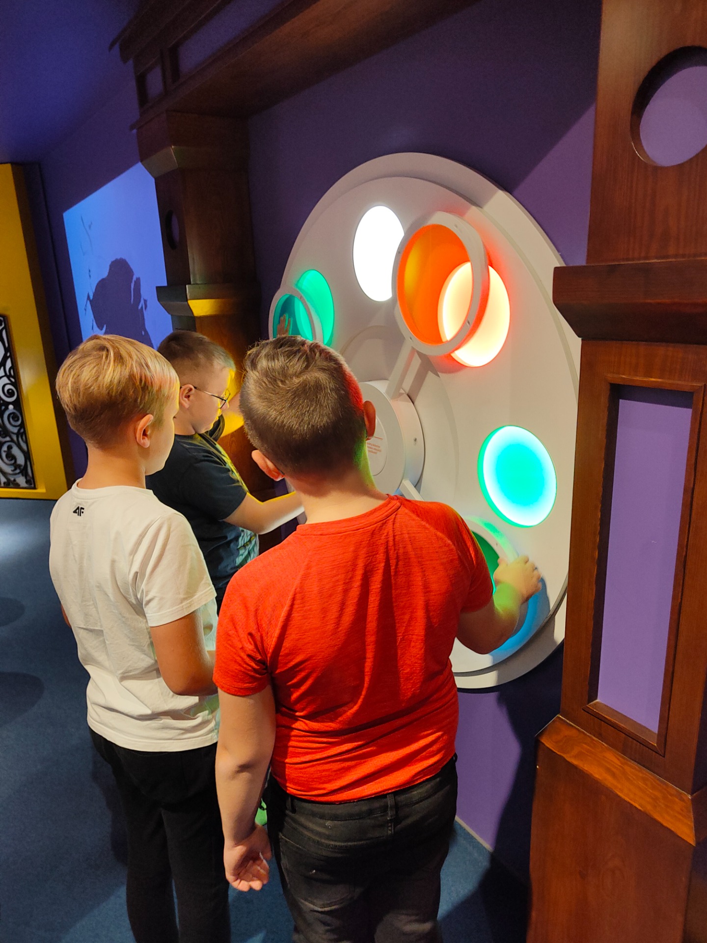 Trójka chłopców stoi przy urządzeniu, które zmienia kolory. 