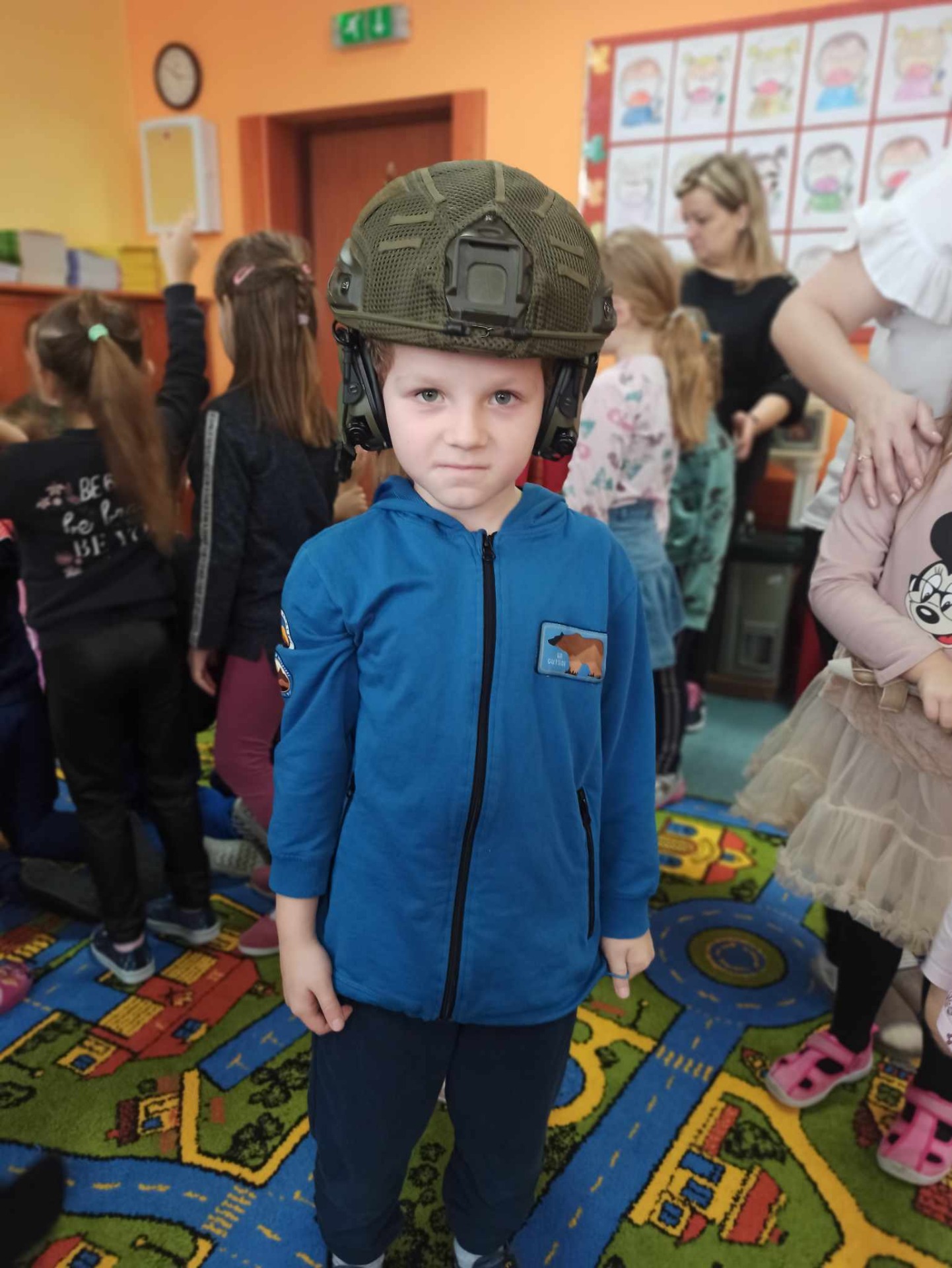 Dzieci z oddziałów przedszkolnych przymierzają hełm wojskowy.